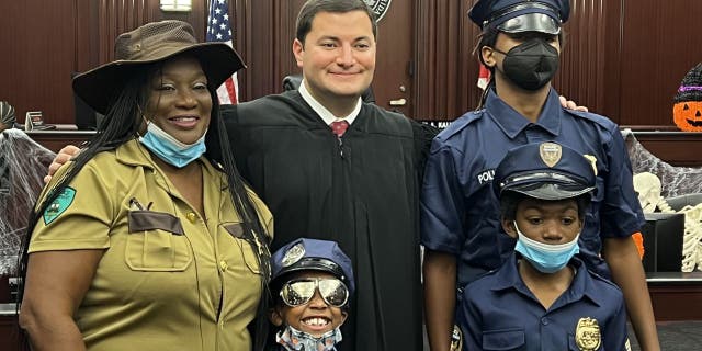 Angie Sheppard and her two sons welcome 8-year-old Shyla into their family. The new family unit posed for a picture with Judge Michael Kalil, who presided over the Halloween-themed adoption ceremony.
