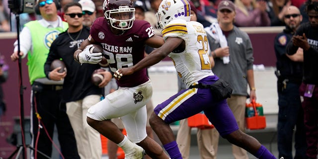 Texas A&M running back Isaiah Spiller (28) fights off a Prairie View A&M safety Drake Cheatum (22) for a 28-yard gain during the first quarter of an NCAA college football game on Saturday, Nov. 20, 2021, in College Station, Texas.