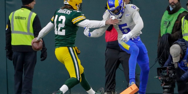 Packers quarterback Aaron Rodgers runs past Los Angeles Rams' Jalen Ramsey for a touchdown Sunday, 十一月. 28, 2021, in Green Bay, 威斯康星州.