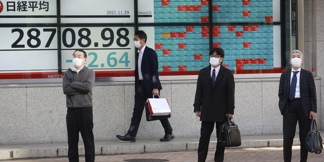 People stand by an electronic stock board of a securities firm in Tokyo on Monday.