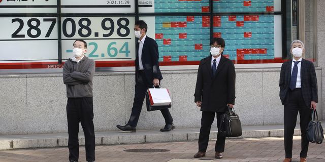 People stand by an electronic stock board of a securities firm in Tokyo on Monday.