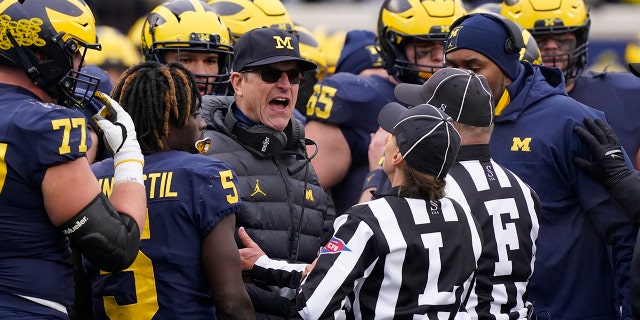 Los árbitros hablan con el entrenador en jefe de Michigan, Jim Harbaugh, durante la segunda mitad de un partido contra Ohio State el 27 de noviembre de 2021 en Ann Arbor, Michigan.