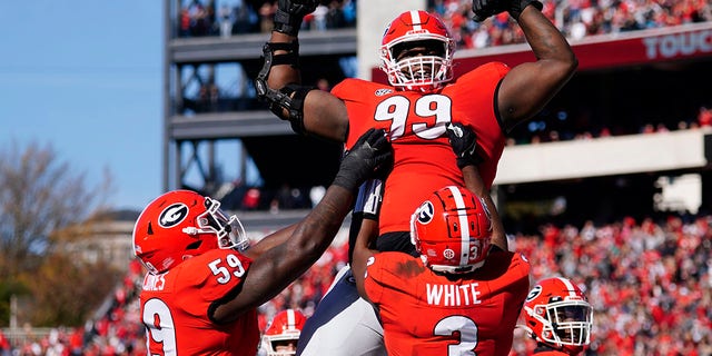 Georgia defensive lineman Jordan Davis (99) is lifted into the air by running back Zamir White (3) and offensive lineman Justin Shaffer (54) after scoring a touchdown in the first half of an NCAA college football game against Charleston Southern, Saterdag, Nov.. 20, 2021, in Athene, Ga..