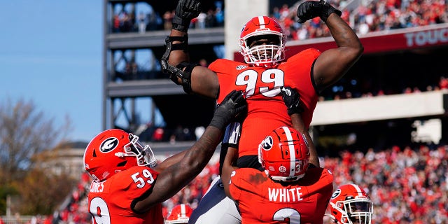 Georgia defensive lineman Jordan Davis (99) is lifted into the air by running back Zamir White (3) and offensive lineman Justin Shaffer (54) after scoring a touchdown in the first half of an NCAA college football game against Charleston Southern, 星期六, 十一月. 20, 2021, in Athens, 嘎。.