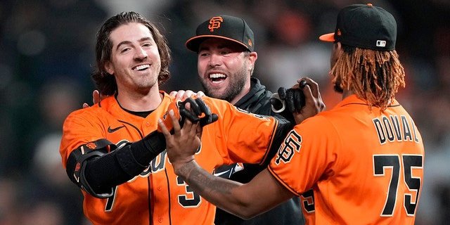 Kevin Gausman #34 and Camilo Doval #75 of the San Francisco Giants celebrates after Gausman hit a pinch hit sacrifice walk-off RBI scoring Brandon Crawford #35 to defeat the Atlanta Braves 6-5 in the bottom of the 11th inning at Oracle Park on September 17, 2021 in San Francisco, California.