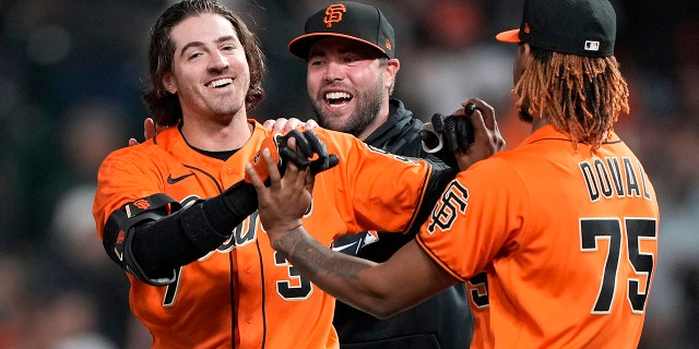 Kevin Gausman #34 and Camilo Doval #75 of the San Francisco Giants celebrates after Gausman hit a pinch hit sacrifice walk-off RBI scoring Brandon Crawford #35 to defeat the Atlanta Braves 6-5 in the bottom of the 11th inning at Oracle Park on September 17, 2021 in San Francisco, California.