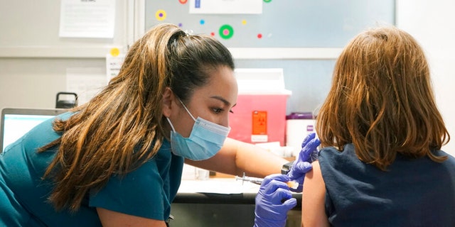 Courtney Martin, left, a nurse at the University of Washington Medical Center, gives the first shot of the Pfizer COVID-19 vaccine to Ani Hahn, 7, Tuesday, Nov. 9, 2021, in Seattle.