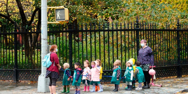 A line of preschool children crossing the street with a teacher