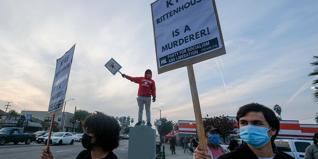 Protesters hold  up a signs, Friday, Nov. 19, 2021, in Los Angeles, following the acquittal of Kyle Rittenhouse in Kenosha, Wisconsin. 