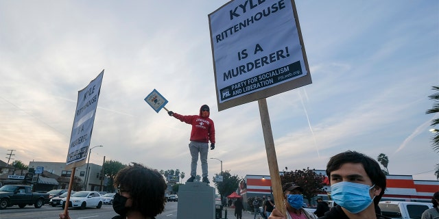 Protesters hold up a signs, viernes, nov. 19, 2021, En los angeles, following the acquittal of Kyle Rittenhouse in Kenosha, Wis. Asserting self-defense, Rittenhouse was acquitted of all charges Friday in the deadly Kenosha shootings that became a flashpoint in the debate over guns, vigilantism and racial injustice in the U.S. (AP Photo/Ringo H.W. Chiu)