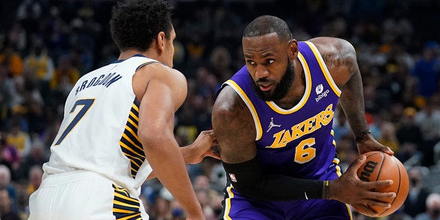 Los Angeles Lakers' LeBron James (6) is defended by Indiana Pacers' Malcolm Brogdon (7) during the first half of an NBA basketball game Wednesday, Nov. 24, 2021, in Indianapolis.
