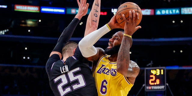 Los Angeles Lakers forward LeBron James (6) is defended by Sacramento Kings center Alex Len (25) during the first half of an NBA basketball game in Los Angeles, Friday, Nov. 26, 2021.