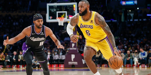 El delantero de los Lakers de Los Ángeles LeBron James (6) drives past Sacramento Kings forward Maurice Harkless (8) during the first half of an NBA basketball game in Los Angeles, viernes, nov. 26, 2021.