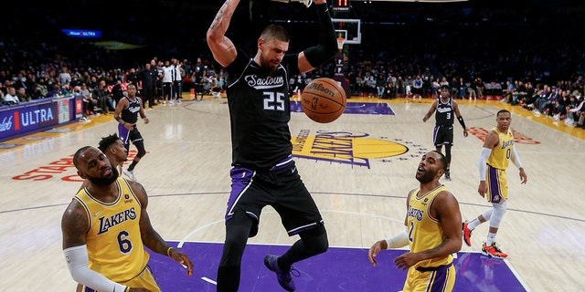 Sacramento Kings center Alex Len (25) dunks between Los Angeles Lakers forward LeBron James (6) and guard Wayne Ellington (2) during the second half of an NBA basketball game in Los Angeles, Vrydag, Nov.. 26, 2021. The Kings won 141-137 in triple overtime.