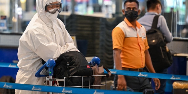 A passenger wearing personal protective equipment queues to check-in for a flight at the Kuala Lumpur International Airport on November 29, 2021, as countries across the globe shut borders and renewed travel curbs in response to the spread of a new, heavily mutated Covid-19 coronavirus variation. (Photo by Mohd RASFAN / AFP)