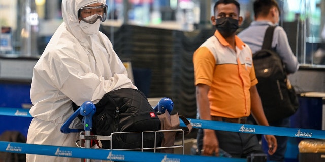 A passenger wearing personal protective equipment queues to check-in for a flight at the Kuala Lumpur International Airport on Nov. 29, 2021, as countries across the globe shut borders and renewed travel curbs in response to the spread of a new, heavily mutated COVID-19 coronavirus variation. (Photo by Mohd RASFAN / AFP)Â 