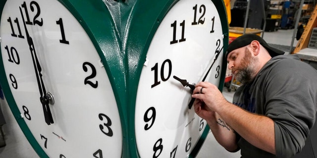 Clock technician Dan LaMoore adjusts clock hands on a large outdoor clock 