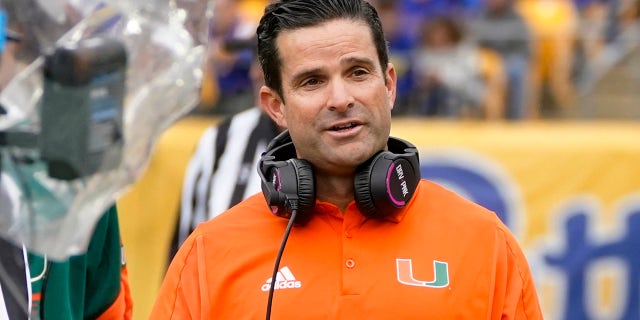 Miami head coach Manny Diaz, right, watches as referee Jeff Heaser, left, looks at a review screen after a targeting penalty was called against Miami during the first half of an NCAA college football game, Saturday, Oct. 30, 2021, in Pittsburgh. The review determined no targeting.