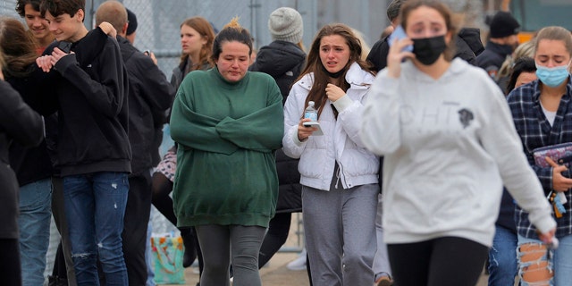 十一月 30, 2021; 牛津, 我, 美国; Parents walk away with their kids from the Meijer's parking lot in Oxford where many students gathered following an active shooter situation at Oxford High School in Oxford on November 30, 2021. Mandatory Credit: Eric Seals-USA TODAY NETWORK
