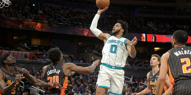 Charlotte Hornets forward Miles Bridges, #0, goes up for a shot between Orlando Magic center Mo Bamba, #5, center Wendell Carter Jr., #34, forward Franz Wagner, #22, and guard Mychal Mulder, #2, during the first half of an NBA basketball game, Wednesday, Nov. 24, 2021, in Orlando, Fla.