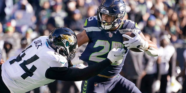 Seattle Seahawks' Travis Homer carries as Jacksonville Jaguars' Myles Jack defends during the first half of an NFL football game, Sunday, Oct. 31, 2021, in Seattle.