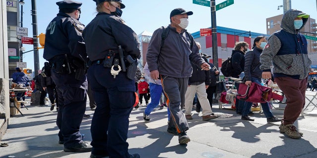 Deux policiers de la ville de New York patrouillent à une intersection très fréquentée de la rue Main à Flushing le 30 mars dans le quartier Queens de New York.