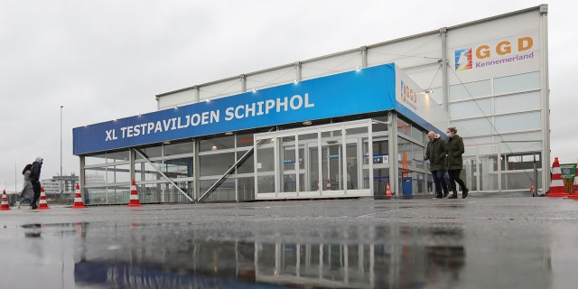 Pessoas caminham do lado de fora do pavilhão de testes XL Schiphol depois que autoridades de saúde holandesas disseram que 61 pessoas que chegaram a Amsterdã em voos da África do Sul testaram positivo para COVID-19, em Amsterdã, Holanda, em 27 de novembro de 2021.