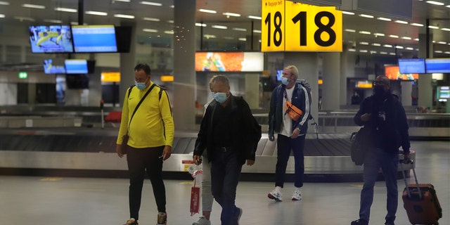 Hollandalı sağlık yetkilileri, Güney Afrika'dan Hollanda'nın Amsterdam kentine uçuş yapan 61 kişinin Covit-19 için pozitif test ettiğini söyledikten sonra, insanlar 27 Kasım 2021'de Schiphol Havalimanı'na girdiler. 