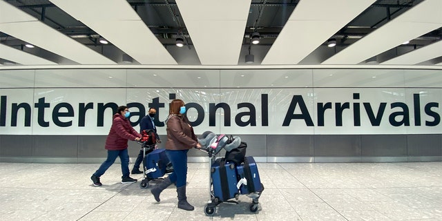 Passengers walk through International Arrivals at London's Heathrow Airport, Friday, Nov. 26, 2021. The U.K. announced that it was banning flights from South Africa and five other South African countries, effective at noon on Friday, and that anyone who had recently arrived from those countries would be asked to take a coronavirus test. 