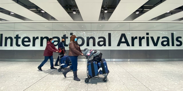 Passengers walk through International Arrivals, at London's Heathrow Airport, Friday, Nov. 26, 2021.