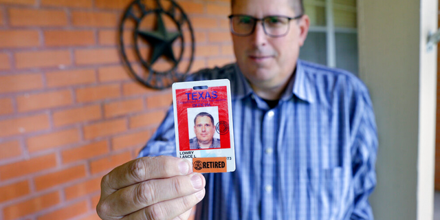 Lance Lowry, a recently retired corrections officer with the Texas State Penitentiary, holds his ID badge on the front porch of his home, Oct. 27, 2021, in Huntsville, Texas.
