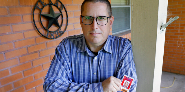 Lance Lowry, a recently retired corrections officer with the Texas State Penitentiary, holds his ID badge on the front porch of his home, Oct. 27, 2021, in Huntsville, Texas.