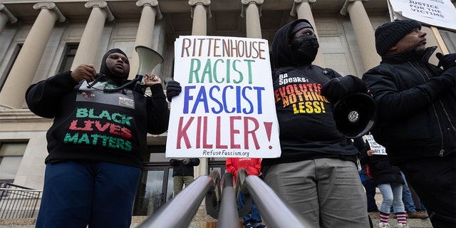 Demonstrators hold signs outside of the Kenosha County Courthouse during closing arguments in the Kyle Rittenhouse trial in Kenosha, Wisconsin, U.S., on Tuesday, Nov. 16, 2021. Rittenhouse, 18, is accused of homicide in the deaths of Joseph Rosenbaum and Anthony Huber, as well as attempted homicide for shooting Gaige Grosskreutz. Photographer: Christian Monterrosa/Bloomberg via Getty Images