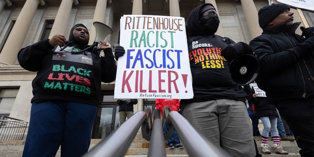 Demonstrators hold signs outside of the Kenosha County Courthouse during closing arguments in the Kyle Rittenhouse trial in Kenosha, Wisconsin, U.S., on Tuesday, Nov. 16, 2021. Rittenhouse, 18, is accused of homicide in the deaths of Joseph Rosenbaum and Anthony Huber, as well as attempted homicide for shooting Gaige Grosskreutz. Photographer: Christian Monterrosa/Bloomberg via Getty Images