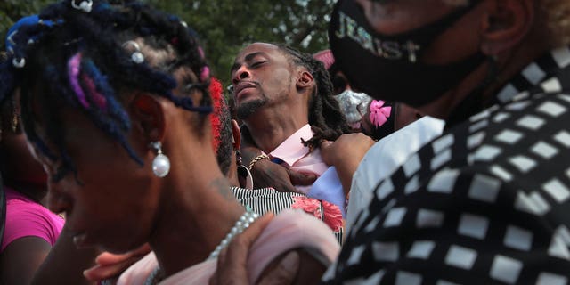 Deontae Davis Sr. is hugged at rear as Elder Carolyn Rice-Smith, right, supports Sabrina Dunigan at the end of burial services for their children at Sunset Gardens of Memory Cemetery in Millstadt, Illinois in August 2021. 