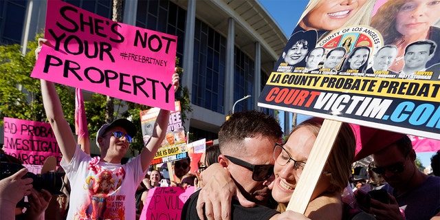 Britney Spears supporters Aaron Morris, second from right, and Elizabeth Crocker embrace outside a hearing concerning the pop singer's conservatorship at the Stanley Mosk Courthouse, Friday, Nov. 12, 2021, in Los Angeles. A Los Angeles judge ended the conservatorship that has controlled Spears' life and money for nearly 14 years. 