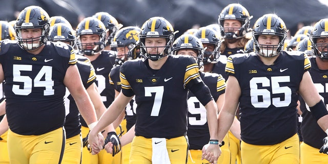 Quarterback Spencer Petras (7), offensive lineman Matt Fagan (54) and offensive lineman Tyler Linderbaum (65) of the Iowa Hawkeyes walk out with teammates before the matchup against the Illinois Fighting Illini at Kinnick Stadium on Nov. 20, 2021, in Iowa City, Iowa. 