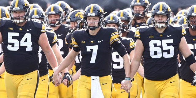 Quarterback Spencer Petras (7), offensive lineman Matt Fagan (54) and offensive lineman Tyler Linderbaum (65) of the Iowa Hawkeyes walk out with teammates before the matchup against the Illinois Fighting Illini at Kinnick Stadium on Nov. 20, 2021, in Iowa City, Iowa.