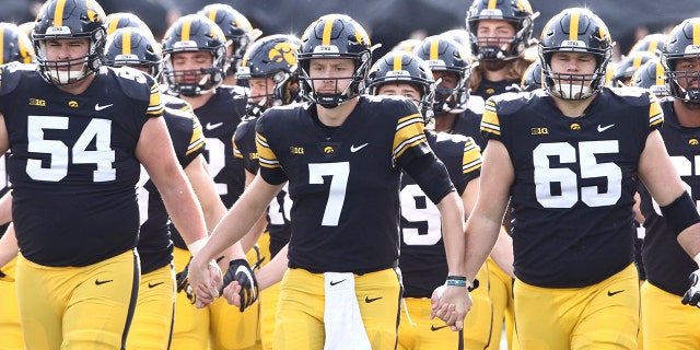 Quarterback Spencer Petras (7), offensive lineman Matt Fagan (54) and offensive lineman Tyler Linderbaum (65) of the Iowa Hawkeyes walk out with teammates before the matchup against the Illinois Fighting Illini at Kinnick Stadium on Nov. 20, 2021, in Iowa City, Iowa. 