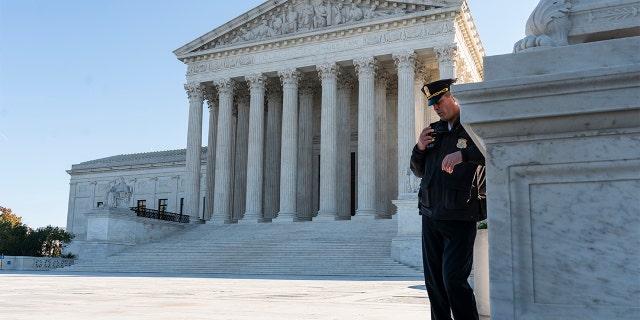 A police officer maintains a watch during a demonstration by victims of gun violence in front of the Supreme Court. 