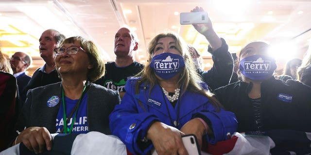 Supporters, some wearing 'Terry For Virginia' protective face masks, listen to Democratic nominee for Virginia Governor Terry McAuliffe speak during his election night party and rally in McLean, Virginia, U.S., November 2, 2021.