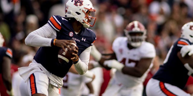 Auburn quarterback TJ Finley (1) rolls away from pressure during the first half of an NCAA college football game against Alabama, Saturday, Nov. 27, 2021, in Auburn, Ala.