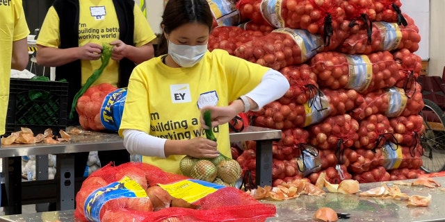 A volunteer is shown packing onions in the warehouse of the Alameda County Community Food Bank in Oakland, Calif., in Nov. 2021.
