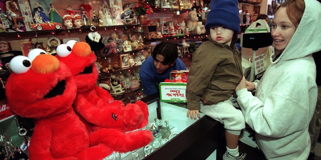 Two-and-a-half year-old Nicholas Barrientos of Culver City and mother, Kristine, check out large Elmos sitting on toy store counter while clerk rings up their Tickle Me Elmo Friday morning. They were among some 50 folks lucky enough to have their lottery ticket drawn for opportunity to purchase the popular doll.  (Photo by Ken Lubas/Los Angeles Times via Getty Images)