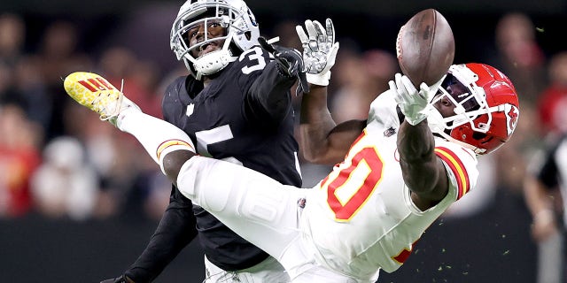 Tyreek Hill #10 of the Kansas City Chiefs and Brandon Facyson #35 of the Las Vegas Raiders try to catch the ball in the first quarter in the game at Allegiant Stadium on Nov. 14, 2021, in Las Vegas, Nevada.