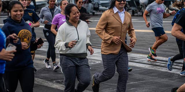 PHILIPPINE SEA, USS Carl Vinson - Lt. Cmdr. Kamille Pizarro, training officer, and Lt. Cmdr. Christopher Grady, chaplain, participate in a Thanksgiving 5k run on the flight deck of Nimitz-class aircraft carrier USS Carl Vinson (CVN 70), Nov. 25, 2021. (U.S. Navy photo by Mass Communication Specialist Seaman Megan Alexander)