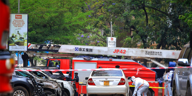 Security forces and forensics officers examine the scene of a blast on a street near the parliamentary building in Kampala, Uganda, Tuesday, Nov. 16, 2021. 