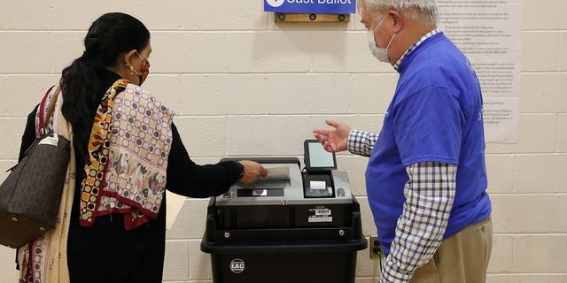 A woman, who preferred not to give her name, gets instructions from an election officer as she casts her ballot at a polling place at the Randolph Elementary School in Arlington, Virginia, on Nov. 2, 2021.