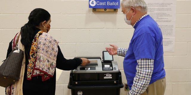 A woman, who preferred not to give her name, gets instructions from an election officer as she casts her ballot at a polling place at the Randolph Elementary School in Arlington, Virginia, on Nov. 2, 2021.