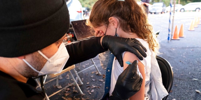 Leah Lefkove, 9, covers her face as her dad Dr. Ben Lefkove gives her the first COVID-19 vaccine at the Viral Solutions vaccination and testing site in Decatur, Ga.  (AP Photo/Ben Gray)